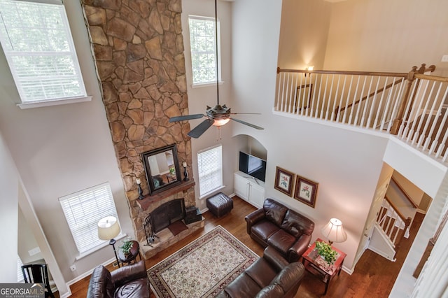 5960 Bridge Stone Ct, Cumming, GA 30028 - living area featuring a ceiling fan, a towering ceiling, wood finished floors, healthy amount of natural light, and a stone fireplace