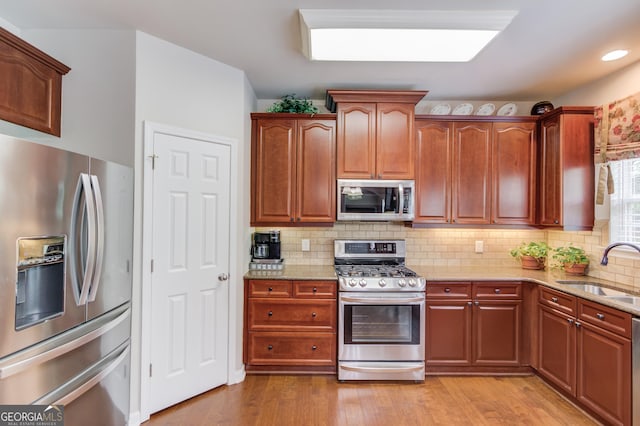 5960 Bridge Stone Ct, Cumming, GA 30028 - kitchen with stainless steel appliances, a sink, light stone countertops, light wood finished floors, and decorative backsplash