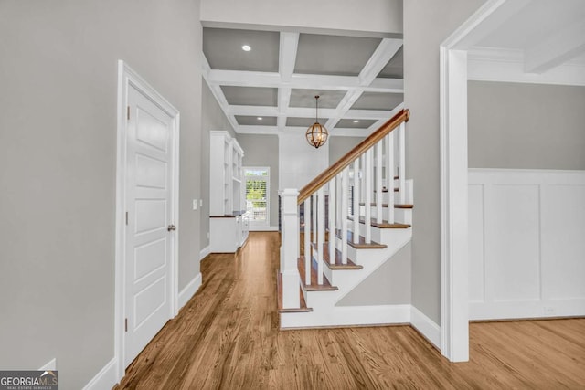 stairs featuring a chandelier, wood finished floors, beam ceiling, coffered ceiling, and baseboards