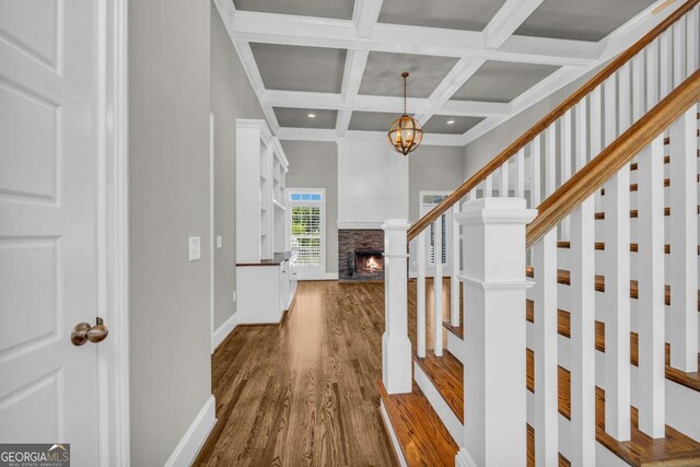 staircase with wood finished floors, coffered ceiling, baseboards, beam ceiling, and a chandelier