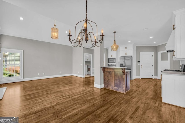 kitchen featuring a chandelier, appliances with stainless steel finishes, dark wood-style flooring, ornamental molding, and white cabinetry