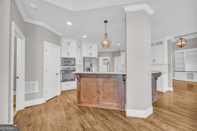 kitchen featuring appliances with stainless steel finishes, crown molding, white cabinets, baseboards, and light wood-type flooring