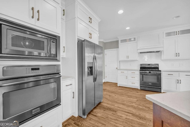 kitchen with stainless steel appliances, white cabinets, light countertops, light wood-type flooring, and ornamental molding