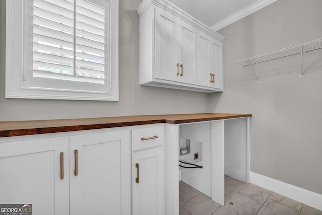 washroom with cabinet space, ornamental molding, light marble finish flooring, and baseboards