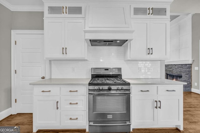 kitchen featuring gas range, baseboards, crown molding, and light countertops
