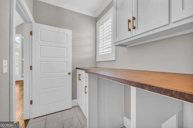 clothes washing area with crown molding, light marble finish floors, and baseboards