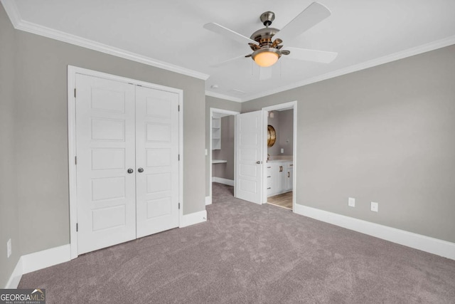 unfurnished bedroom with a closet, carpet floors, baseboards, crown molding, and connected bathroom