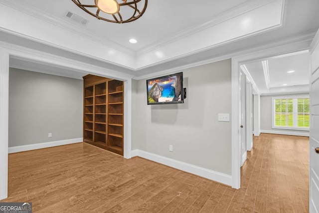 spare room with crown molding, wood finished floors, baseboards, a tray ceiling, and recessed lighting