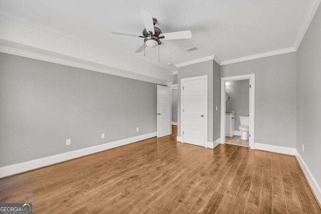 unfurnished bedroom with ornamental molding, baseboards, wood finished floors, ensuite bathroom, and a ceiling fan