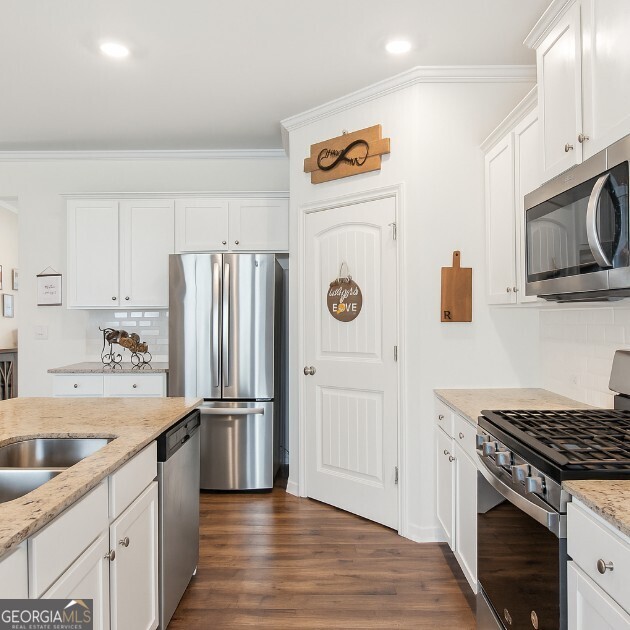 42 Waterfall Ct, Dawsonville, GA 30534 - kitchen with stainless steel appliances, backsplash, crown molding, white cabinets, and light stone countertops