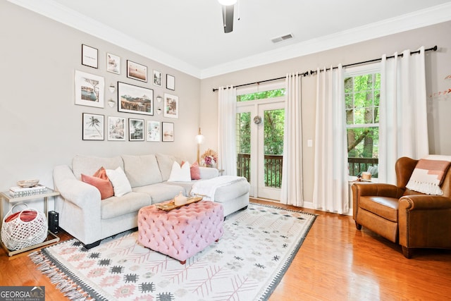 living area featuring ornamental molding, plenty of natural light, and wood finished floors