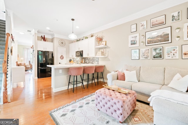 living area with ornamental molding, light wood-type flooring, and recessed lighting