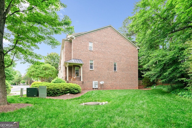 rear view of property featuring brick siding, a lawn, and a standing seam roof