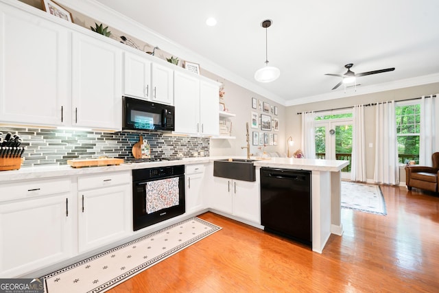 kitchen with black appliances, light wood-style flooring, ornamental molding, backsplash, and white cabinetry