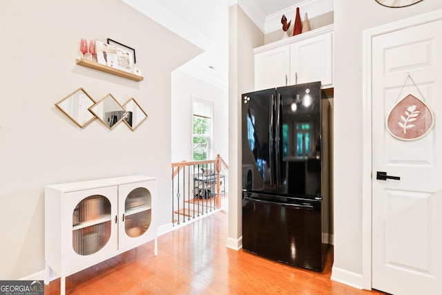 kitchen with freestanding refrigerator, crown molding, light wood-style flooring, white cabinetry, and baseboards