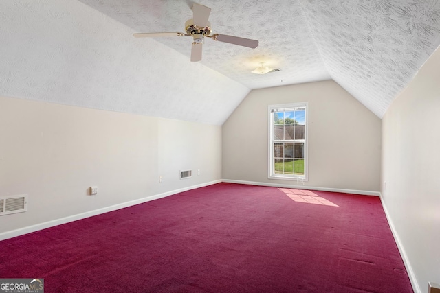 additional living space featuring a textured ceiling, baseboards, lofted ceiling, a ceiling fan, and carpet flooring