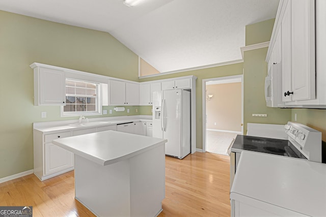 kitchen with white appliances, a sink, light wood-style flooring, vaulted ceiling, and white cabinetry