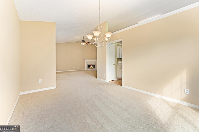 empty room featuring light colored carpet, a chandelier, baseboards, a lit fireplace, and lofted ceiling