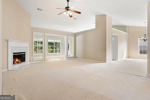 unfurnished living room with vaulted ceiling, a premium fireplace, carpet flooring, ceiling fan, and a chandelier