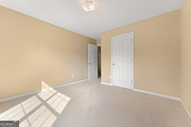 unfurnished bedroom featuring light colored carpet and baseboards