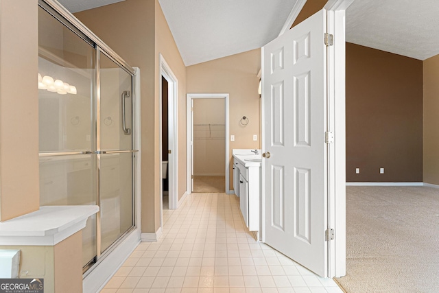 bathroom featuring a shower stall, vanity, a spacious closet, baseboards, and lofted ceiling