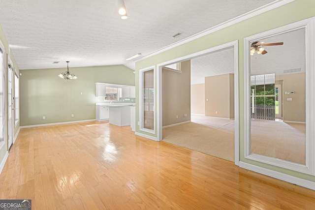 unfurnished living room with a chandelier, baseboards, light wood-style flooring, lofted ceiling, and ceiling fan