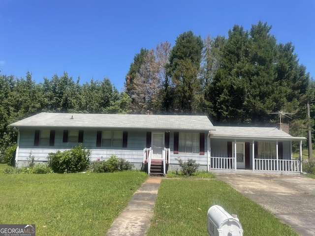 view of front of house with covered porch, a front yard, driveway, and a chimney
