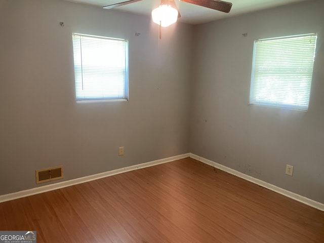 spare room with healthy amount of natural light, a ceiling fan, wood finished floors, and baseboards