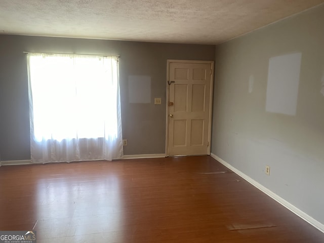 unfurnished room with wood finished floors, baseboards, and a textured ceiling