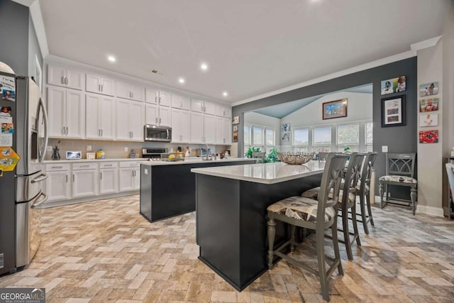 170 Oakleigh Manor Dr, Fayetteville, GA 30215 - kitchen with stainless steel appliances, a center island, white cabinetry, light countertops, and a breakfast bar area