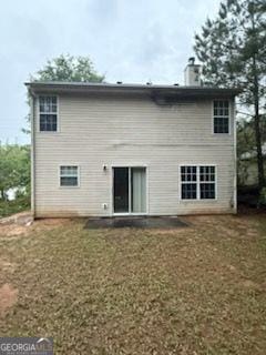 rear view of property with a chimney and a lawn