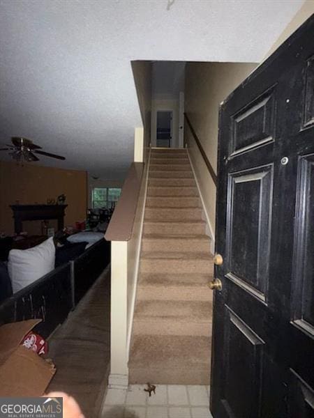 stairs with a ceiling fan and tile patterned floors