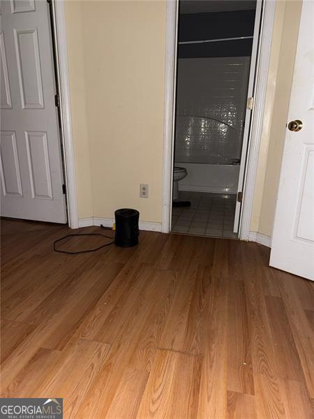 unfurnished bedroom featuring baseboards, wood finished floors, and connected bathroom