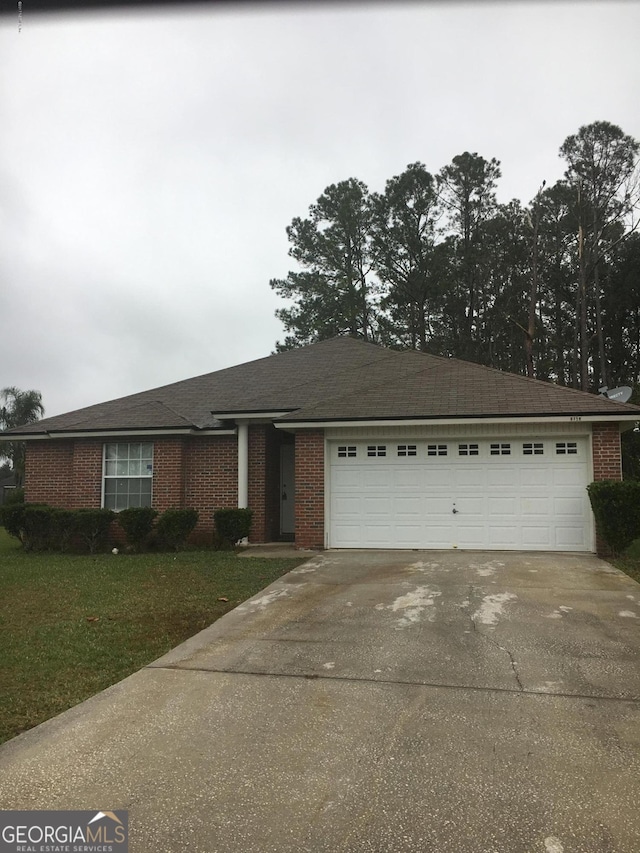ranch-style home with driveway, brick siding, a garage, and a front lawn