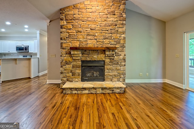 unfurnished living room featuring lofted ceiling, dark wood finished floors, a fireplace, baseboards, and recessed lighting