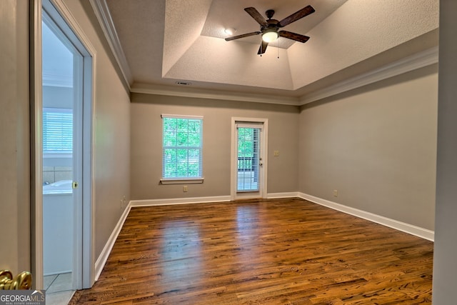 spare room with a raised ceiling, dark wood-style floors, a ceiling fan, crown molding, and a textured ceiling