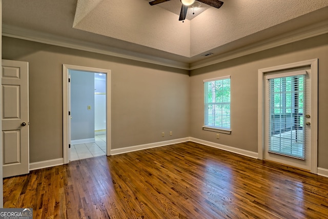 unfurnished room featuring a ceiling fan, dark wood-style flooring, crown molding, a textured ceiling, and a raised ceiling