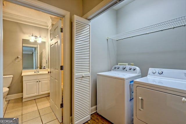 laundry room featuring washer and dryer, crown molding, baseboards, and light tile patterned floors