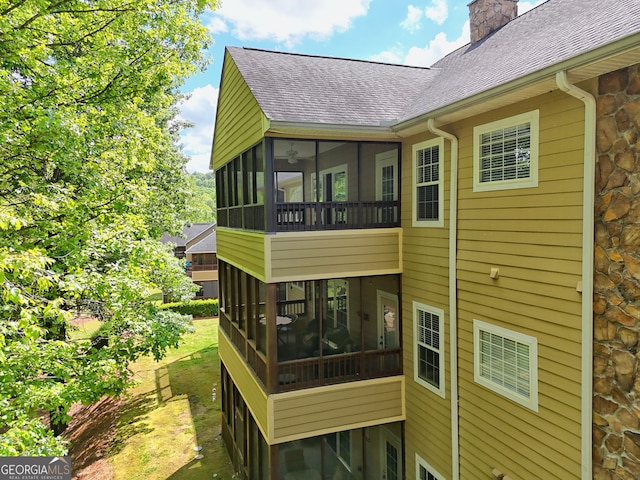 back of property featuring a sunroom, a shingled roof, and a chimney