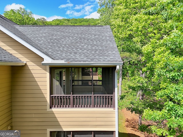 view of side of home with roof with shingles
