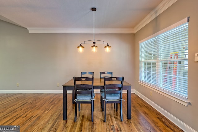 dining area with wood finished floors, crown molding, and baseboards