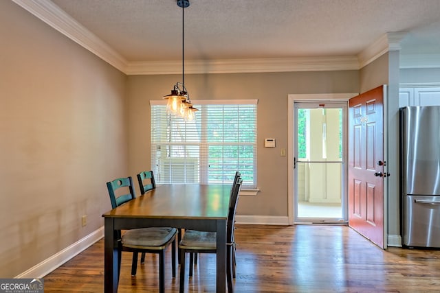 dining room featuring dark wood-type flooring, ornamental molding, baseboards, and a textured ceiling