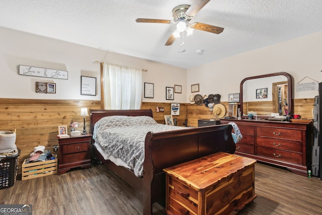 328 Willow Creek Rd, Folkston, GA 31537 - bedroom with wooden walls, a wainscoted wall, dark wood-style flooring, a textured ceiling, and ceiling fan