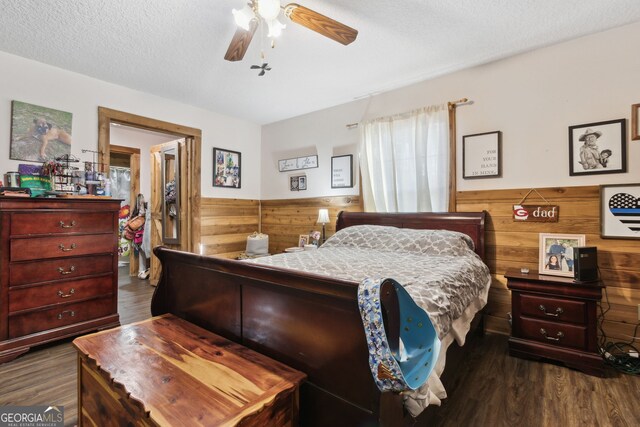 328 Willow Creek Rd, Folkston, GA 31537 - bedroom featuring dark wood-style floors, wooden walls, a wainscoted wall, ceiling fan, and a textured ceiling