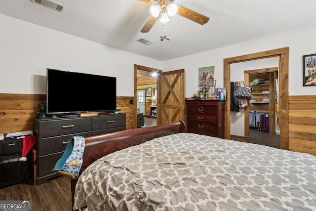 328 Willow Creek Rd, Folkston, GA 31537 - bedroom featuring wood walls, dark wood-style flooring, wainscoting, a textured ceiling, and ceiling fan