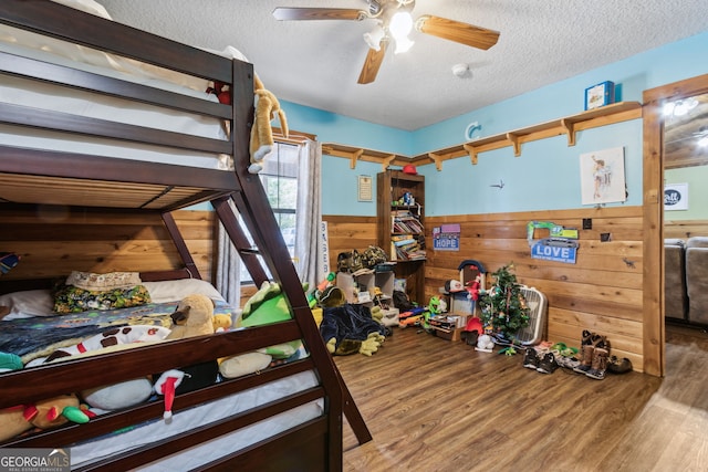 328 Willow Creek Rd, Folkston, GA 31537 - bedroom with wainscoting, a textured ceiling, wooden walls, wood finished floors, and ceiling fan