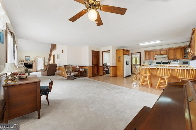 living area with a ceiling fan and light colored carpet
