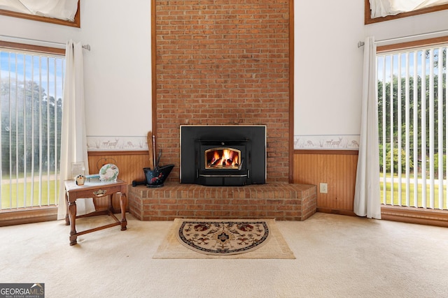 carpeted living room featuring wainscoting, a fireplace, healthy amount of natural light, and wooden walls