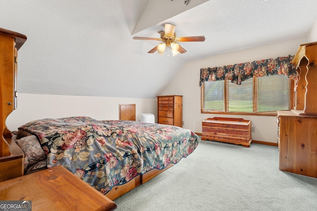 bedroom with carpet flooring, vaulted ceiling, a ceiling fan, and a textured ceiling