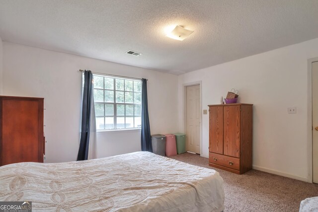 bedroom featuring light colored carpet and a textured ceiling